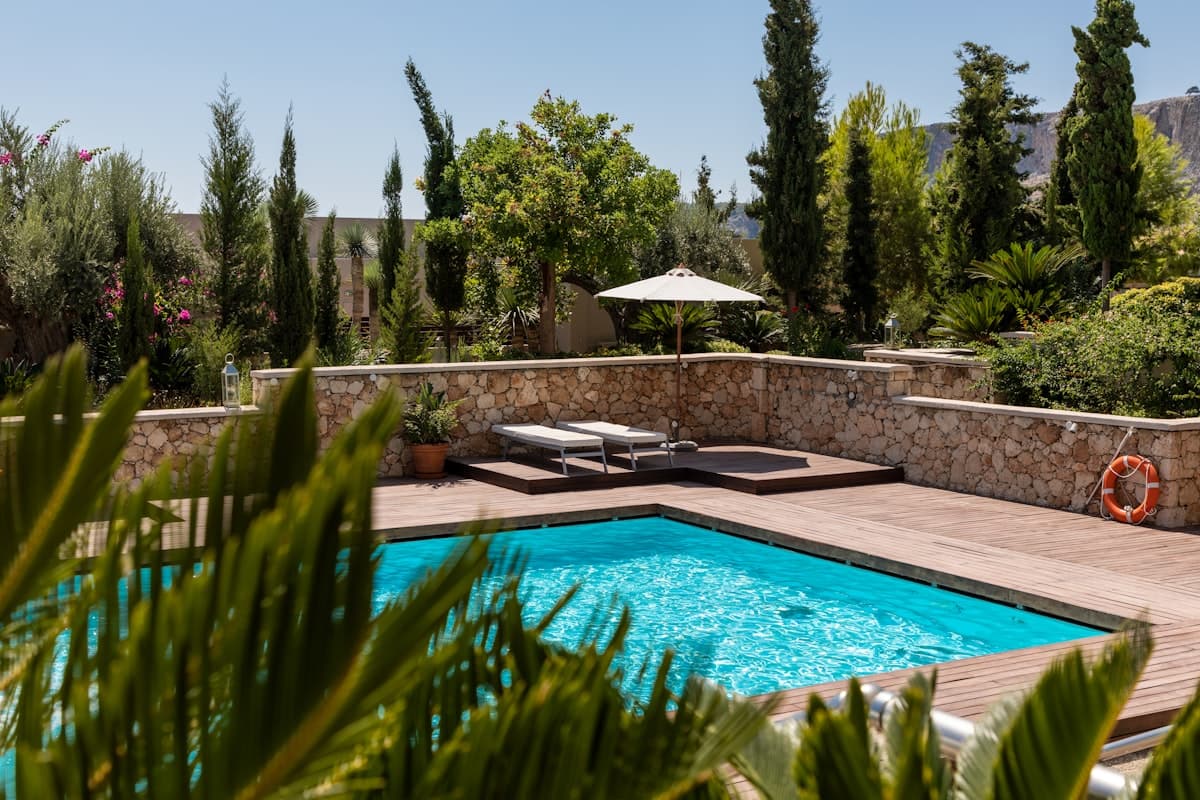 Backyard swimming pool with a stone surround and deck loungers